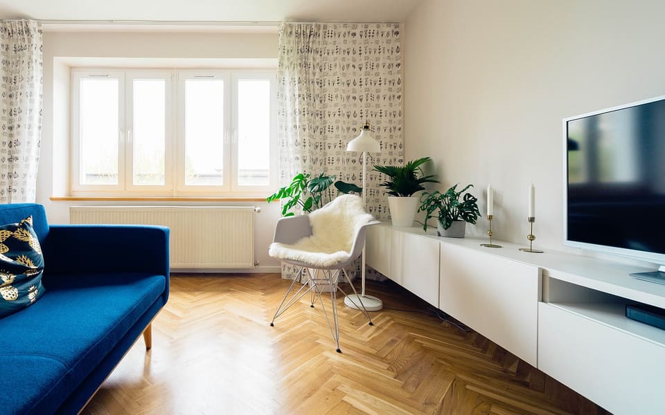 Heller Wohnraum mit Fenster, Pflanzen und Parkettboden