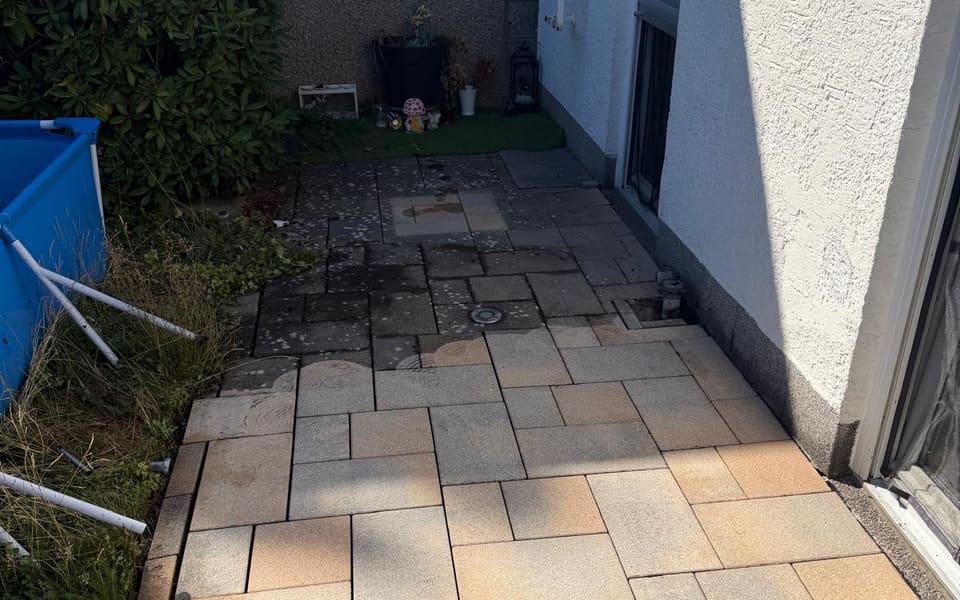 Terrassenplatten während der Hochdruckreinigung — vorn gereinigt, hinten noch belegt